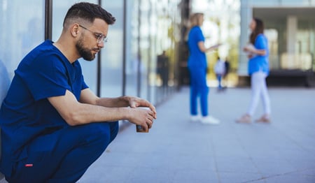 A healthcare worker struggling with mental health outside building