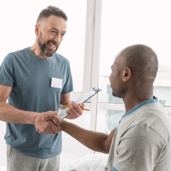 mature doctor shaking hands with black male patient crop