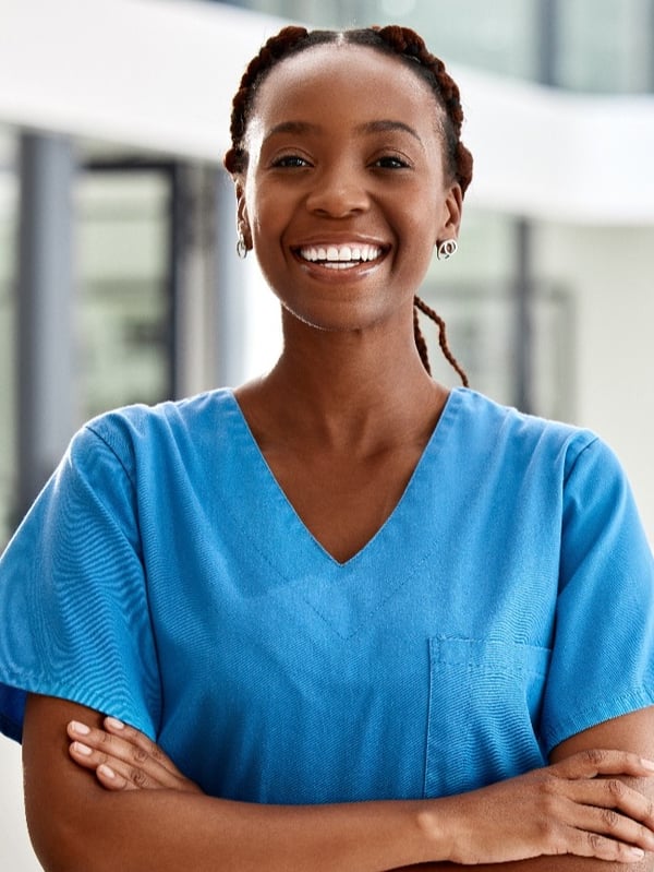 smiling black female in O-R scrubs with two females wearing lab coats in background crop