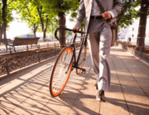 male office worker wearing suit and tie walking bike in public park-1