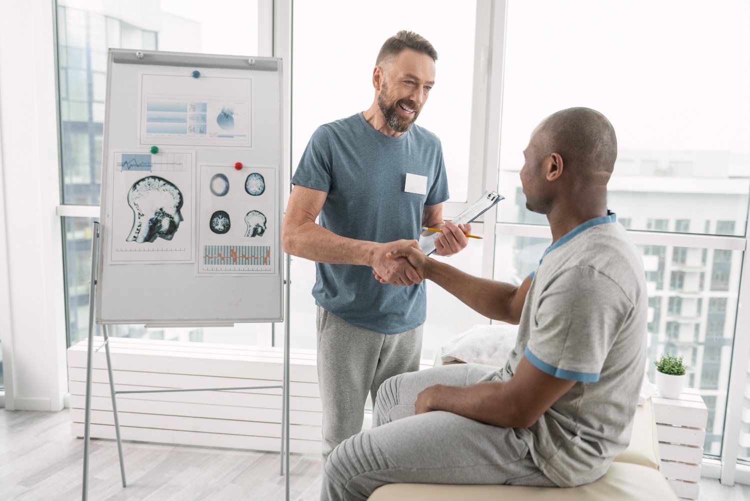 mature doctor shaking hands with black male patient